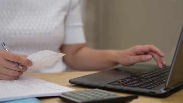 Woman Using Calculator to Calculate Bills at the Table in Office alt