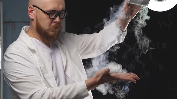 A Male Chemist Pours Liquid Nitrogen on His Hand Which Turns Into White Vapor alt