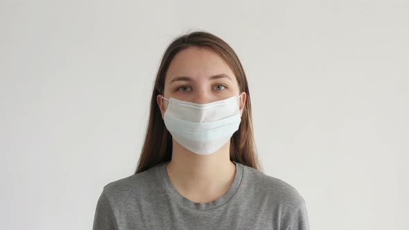 Woman Puts on a Face Mask on White Background. Coronavirus COVID-19.