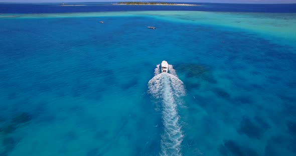 Aerial drone view of a motor boat going to a scenic tropical island in the Maldives alt