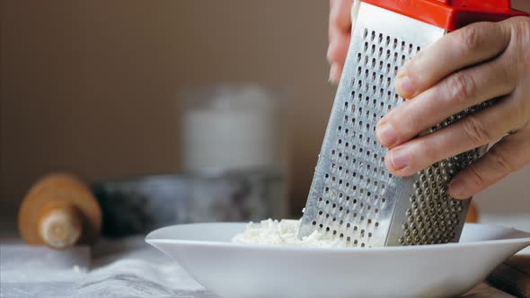Close-up Hands of Mature Woman Is Rubs a Cheese on a Steel Grater