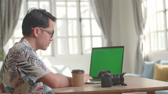 Photographer Works In Photo Editing App / Software On His Laptop Computer With Green Screen Display alt