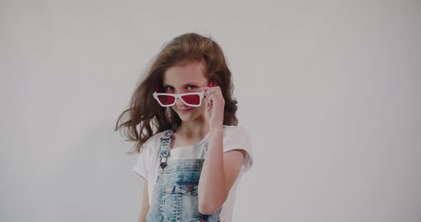Observation gesture. Young girl peeking out over red glasses. Isolated.	