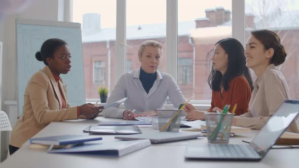 Group of Four Businesswomen Listening to Unrecognizable Speaker alt