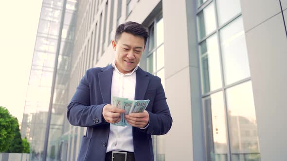 Happy successful asian businessman counts, waves, throws, money background a modern office  alt