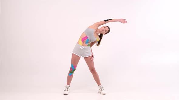 full length portrait female athletes with a kinesiotape on her body doing fitness exercises  alt