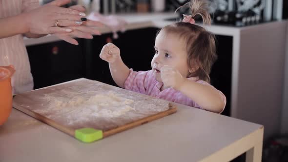 Little Girl Cooking with Caring Mother at Kitchen