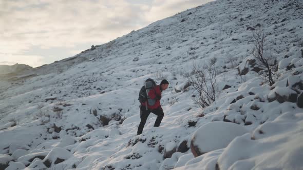 Mature Man Hiking With Backpack In Snow alt