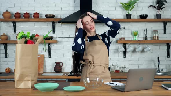 Funny beautiful woman housewife in beige apron dancing sings in home kitchen alt