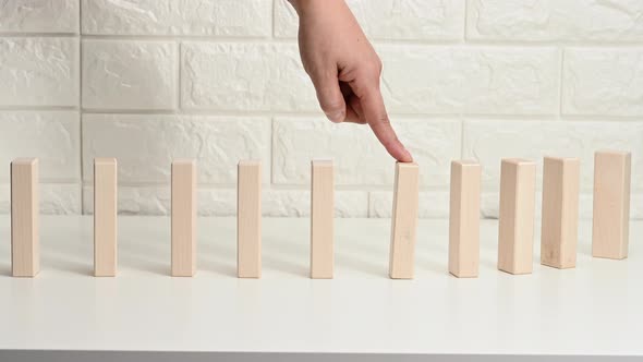 falling wooden blocks on a white table, finger pushes the first block alt
