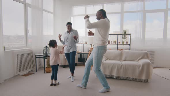 African Happy Family Dancing Together at Home in Living Room at Weekend Celebrate Having Fun Active alt