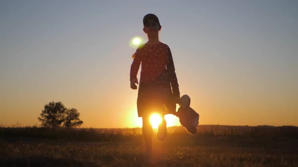 Little Girl in Dress Holding Teddy Bear Toy at Sunset alt