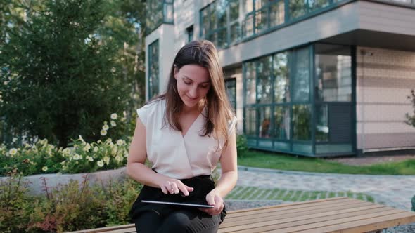 Young Business Woman Who Surfs the Internet on a Tablet Outdoors alt