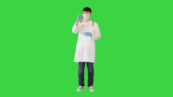Young Asian Doctor Comparing Two Ampules with Red and Blue Solution on a Green Screen Chroma Key