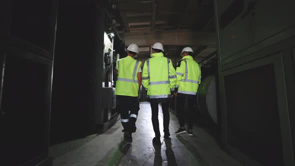 Three Heavy Industry Engineers in Hard Hats Walk in Steel Metal Manufacturing Factory