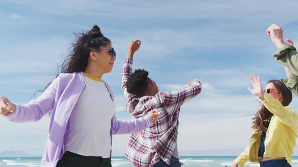 Happy group of diverse female friends having fun, dancing and smiling at the beach alt