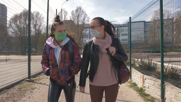 Mother and Daughter a Teenager Walking Down the Street in Protective Masks