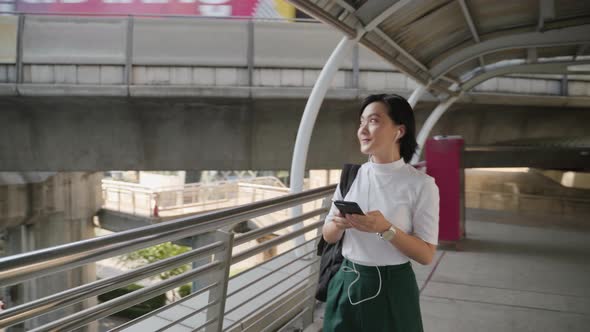 Portrait of asian woman with earphone listening music and using smartphone