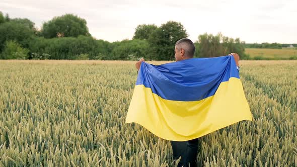 A Man Walked Across the Wheat Field with the Ukrainian Flag on His Back