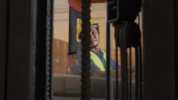 Asian old man working in warehouse and sitting on forklift moving boxes by forklift alt