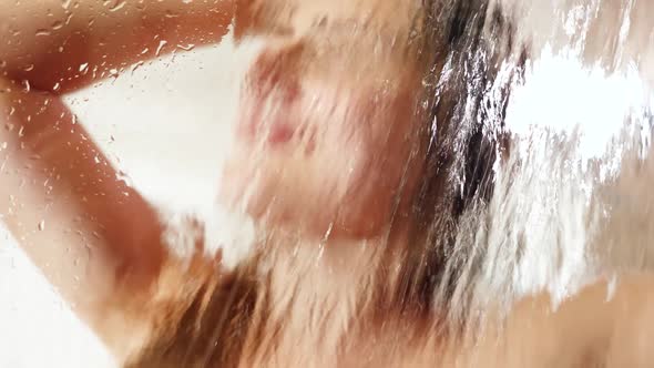 Portrait Through Wet Shower Glass on Smiling Happy Woman Washing Hair and Relaxing in Shower alt