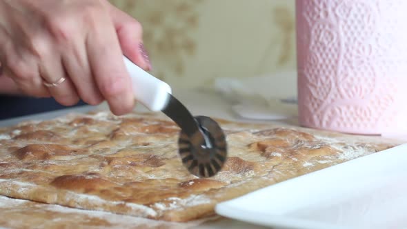 A Woman Cuts A Baked Cake Base. The Woman's Hands And Knife Are Visible. Close Up Shot. alt