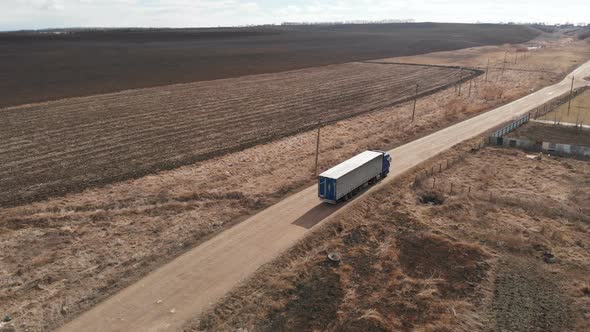 Aerial View of a Large Truck with a Trailer Driving Along a Dirt Road in Search of a Place for a U alt