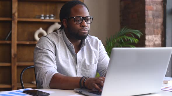 Sad Young African American Male Employee Using a Laptop alt