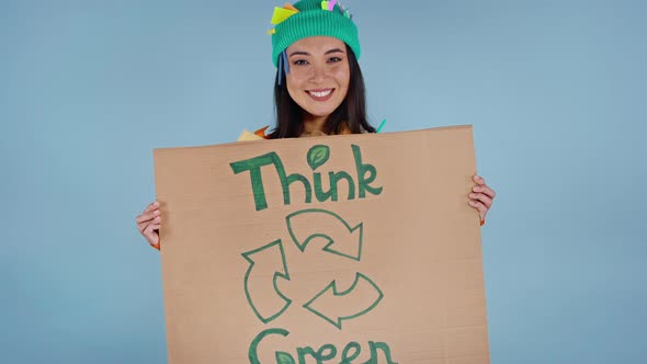 Woman holding cardboard with inscription think green on it