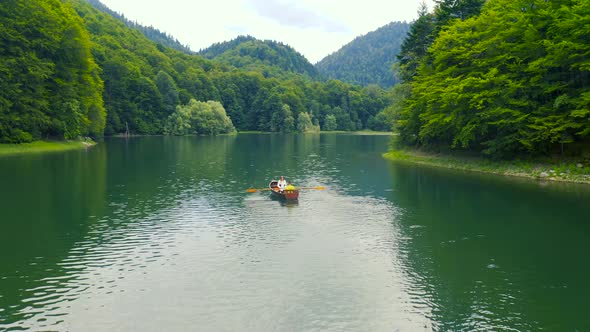 Young Couple on a Wooden Boat on the Biogradsko Lake in Montenegro alt