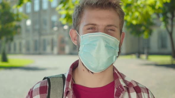 Close-up of Young Man with Brown Eyes Standing Outdoors in Face Mask. Portrait of Male Caucasian alt