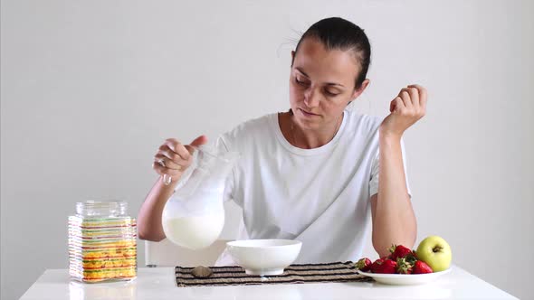 Young Woman is Having a Breakfast Cornflake with Milk and Fruits