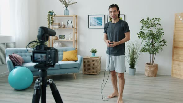 Mixed Race Man Skipping on Jumping Rope and Recording Video for Internet Vlog at Home alt