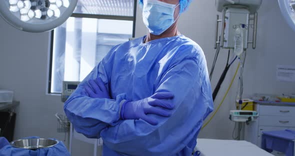 Portrait of male caucasian surgeon wearing face mask and scrubs in hospital alt
