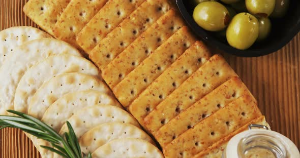 Bowl of green olives, spices, crispy biscuits, jam, rosemary herb, cheese and walnuts alt
