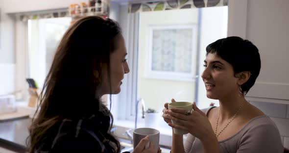 Happy girl friends lesbian couple enjoying a cup of tea or coffee in their ne