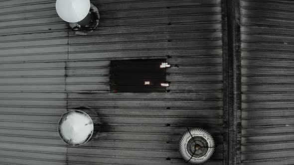 Top view of a black roof full of chimney pipes and turbolent chimney cowls alt