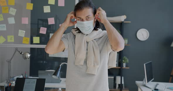 Slow Motion Portrait of Young Entrepreneur Putting on Medical Mask in Office During Pandemic alt
