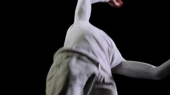 Male Gymnast in White Clothes on a Black Background Jumping on a Trampoline in Slow Motion alt