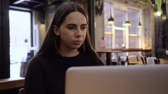 Young Beautiful Brunette Works on a Laptop Computer in Cool Creative Agency in a Loft Office. She