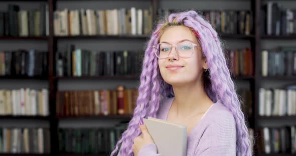 Portrait of a Young Woman with Long Colored Purple Hair and Nose Piercing Standing in the Library