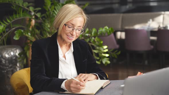 Beautiful Blond Business Lady Sitting at a Table During Business Meeting