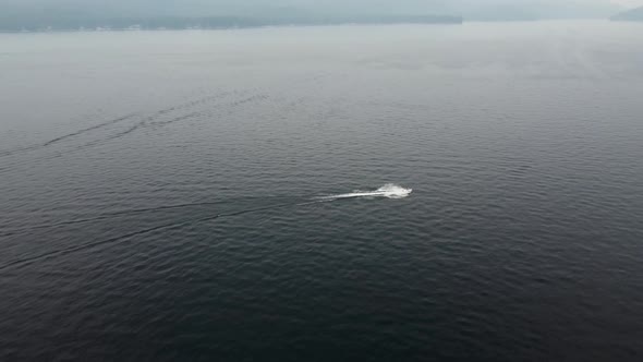 Clockwise drone shot of a jet ski driving on Payette Lake in McCall, Idaho on a smoky day. This stun alt