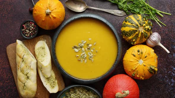 Delicious Pumpkin Soup with Cream Sumflower Seeds and Garlic Toasts on Dark Rusty Background
