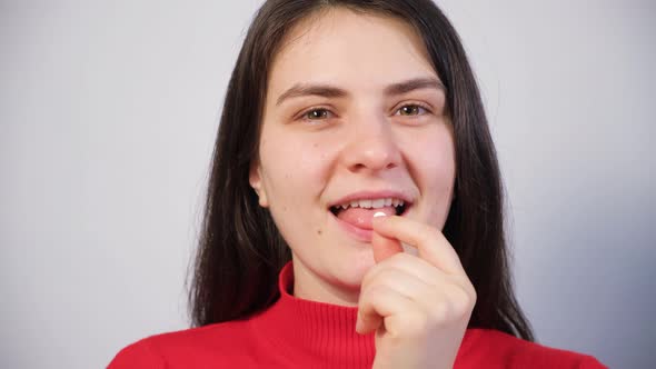 A Beautiful Woman Takes a Pill Shows It on Her Tongue and Smiles alt