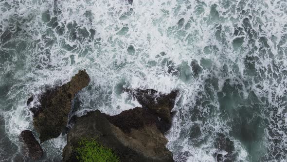 Top down aerial view of giant ocean waves crashing and foaming in coral beach alt