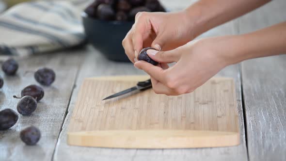 Woman cooking and cutting plum on wooden cutting board. Preparing healthy food. alt