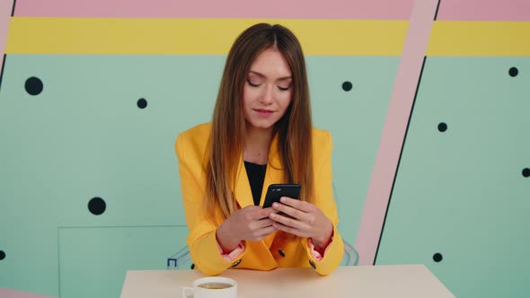 Young Brunette Lady In Yellow Jacket Uses Gadget