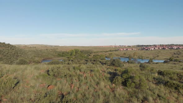 AERIAL Reverse Shot of a DAM in a Green Valley with Housing in the BACK alt