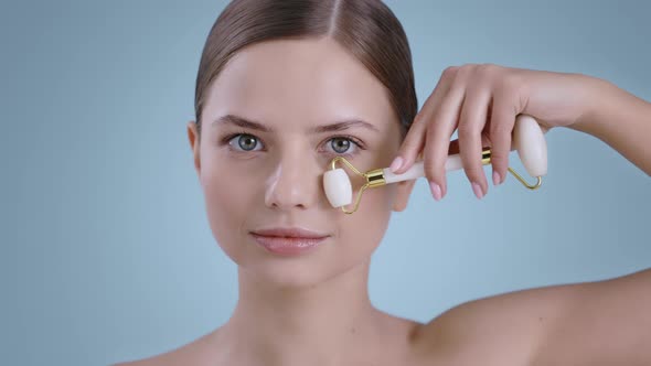 Portrait of Seductive Woman Using Facial Massage Roller and Smilling While Looking to Camera alt